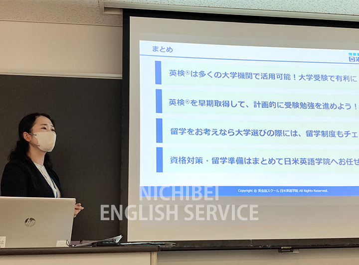 スクリーンを利用しプレゼント行う日米英語学院のスタッフ