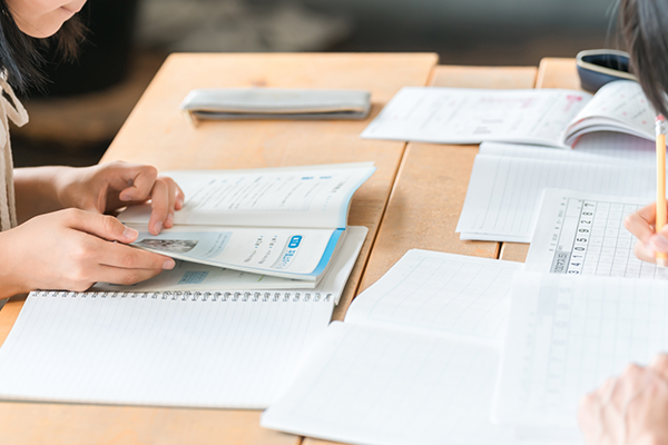 机にいっぱい資料を広げて勉強している人の様子