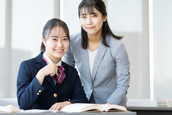 勉強する高校生の背中をしっかりと支えている講師の写真