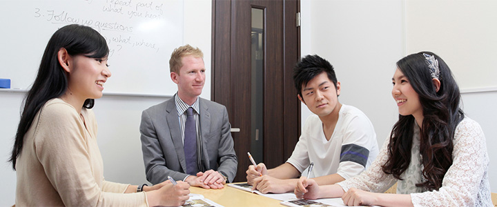 オンライン英会話部の活動イメージ。外国人講師と生徒3名が談笑している様子。