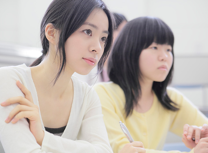 大学構内で授業を真剣に聞く学生のイメージ画像