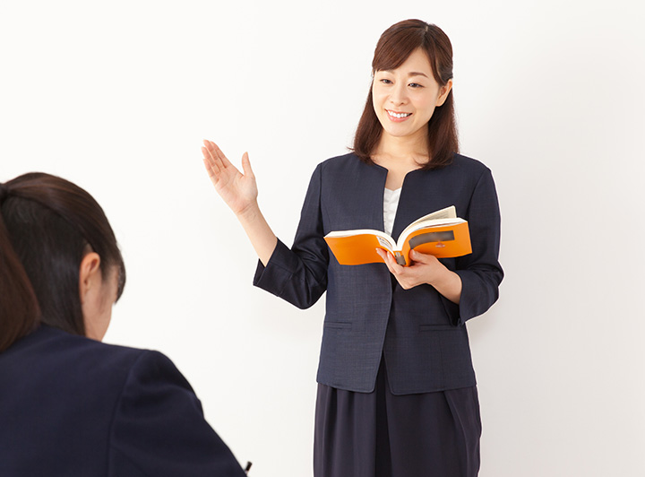 リスニングのコツを教える講師のイメージ画像。手をあげて笑顔で説明している。