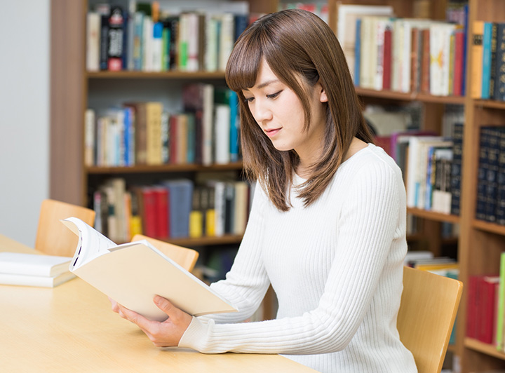 机に広がった白紙のノートと洋書、文房具のイメージ写真