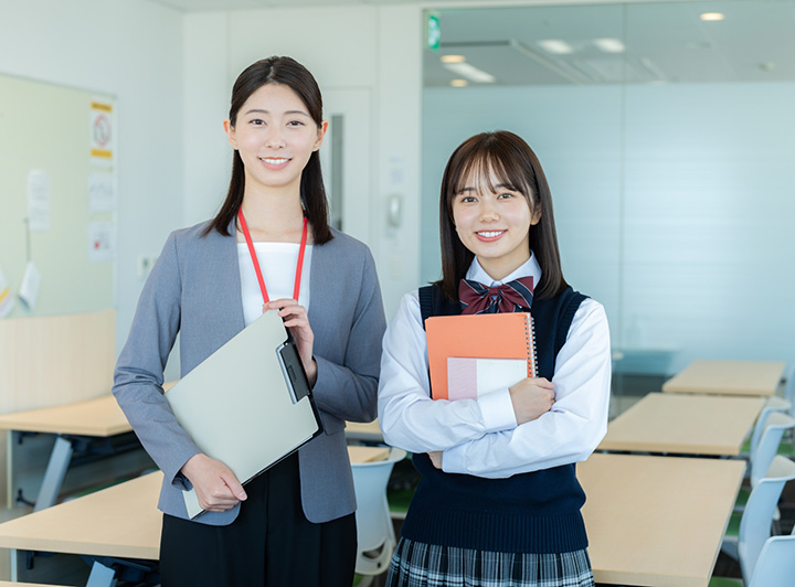 教室内で講師と生徒が並んで笑顔で立っているイメージ画像