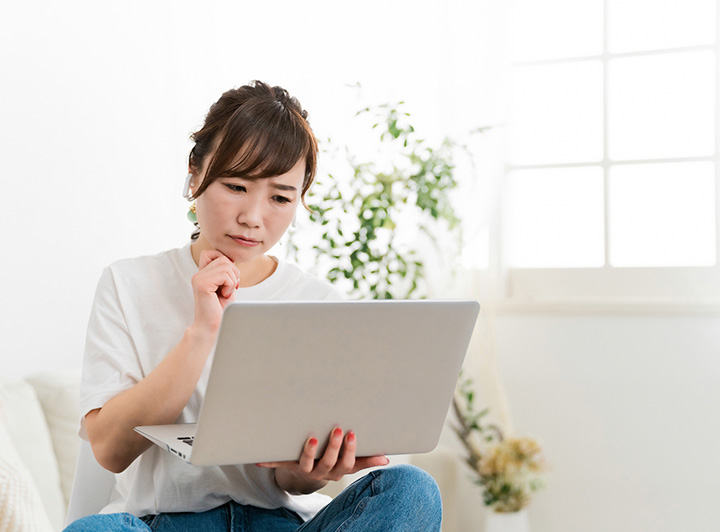 眉間にしわを寄せ、ノートパソコンとにらめっこをしている女性