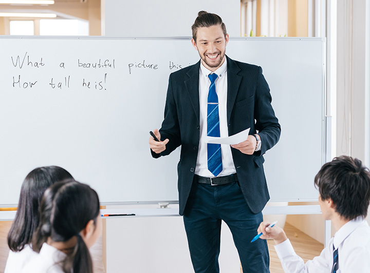 講師からの指導を笑顔でノートにつづる女子高校生のイメージ画像
