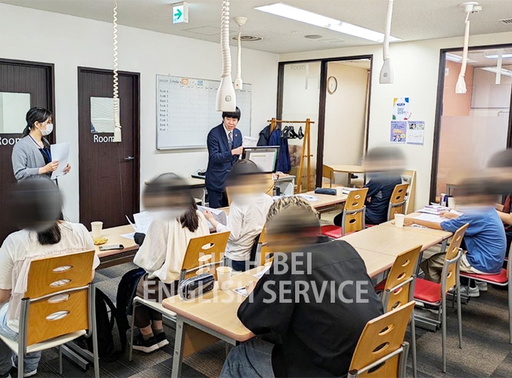 円形テーブルで議論を交わす5人の大学生のイメージ画像
