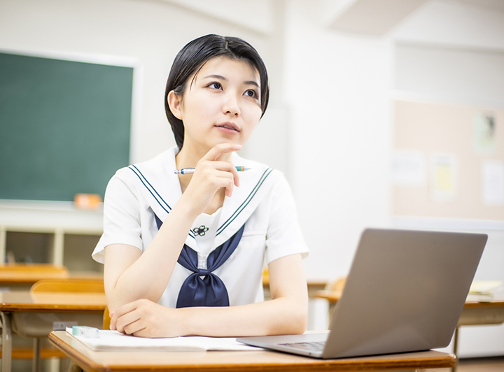 講師からの指導を笑顔でノートにつづる女子高校生のイメージ画像