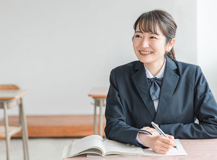 正面を向いて教室で授業を受ける女子高校生のイメージ画像