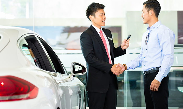 Asian Car Salesman selling auto to customer