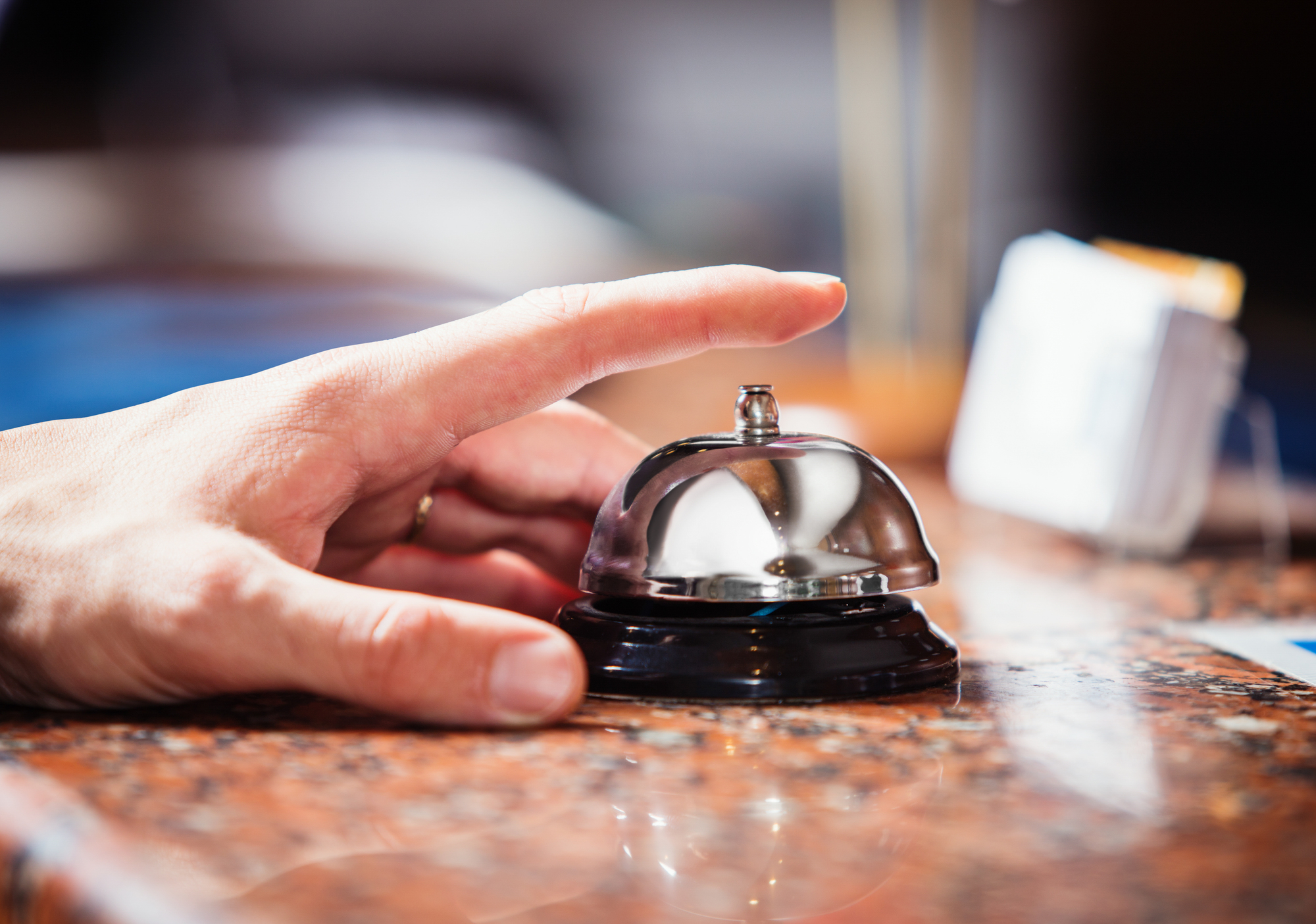 Close up photo of hand ringing a hotel reception service bell t