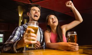 Happy friends drinking beer and cheering together in a bar