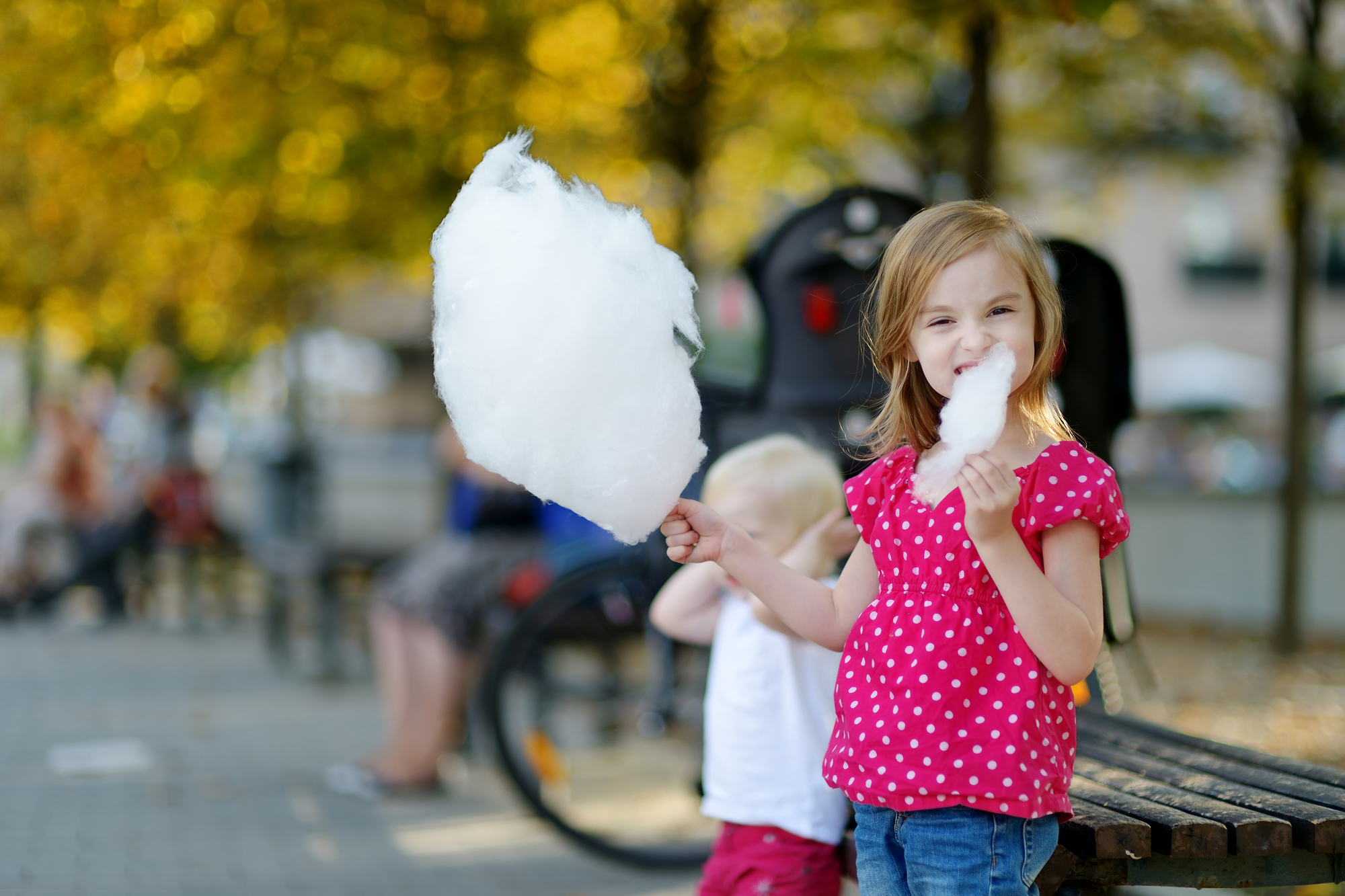 Adorable little girl eating candy-floss outdoors