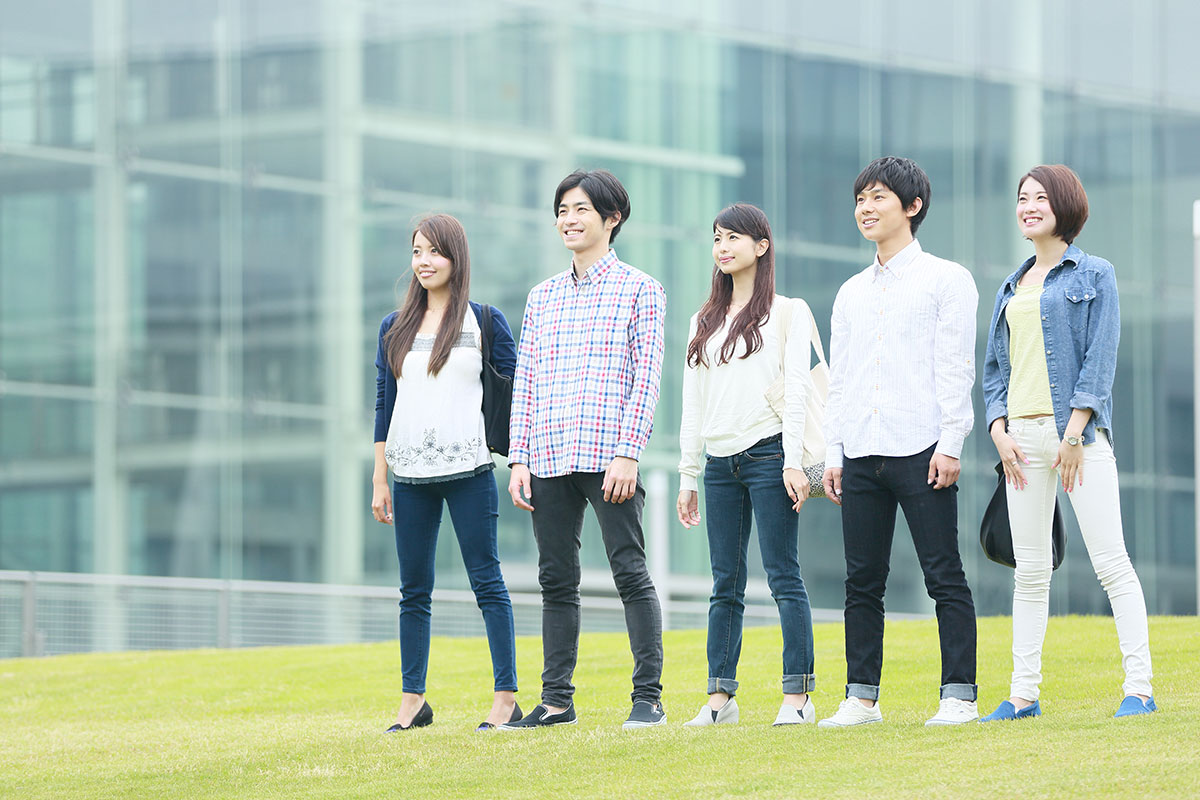 【本文用】芝生の上に立つ男女大学生