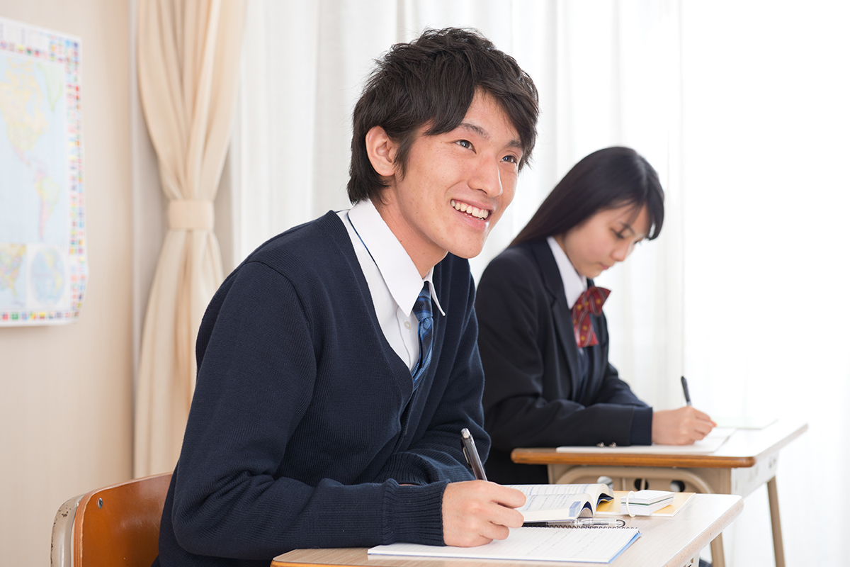 【本文用】笑顔でノートにメモを取る男子学生