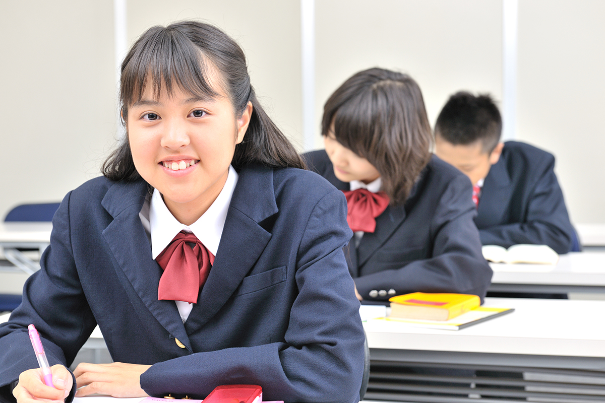 【本文用】勉強中に正面を向き笑顔を見せる女子学生