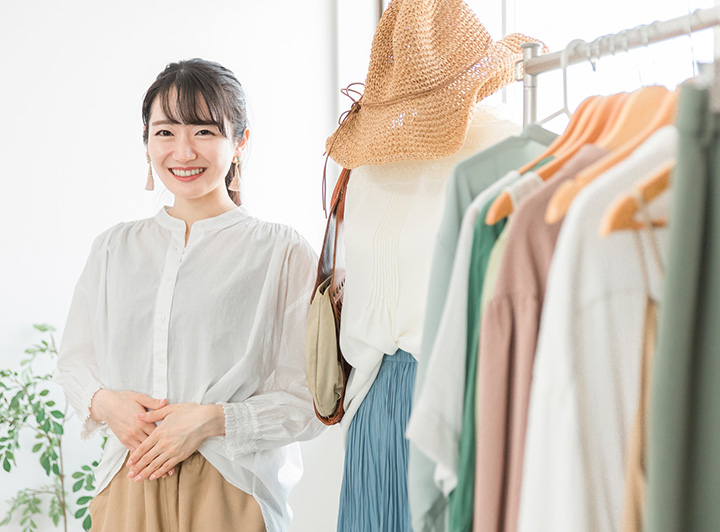 ハンガーに並ぶ洋服と接客をしている女性店員のイメージ