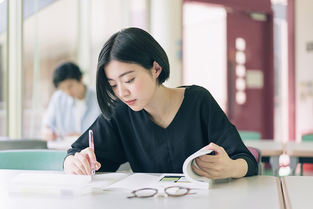 図書館で勉強をする女子大学生のイメージ画像