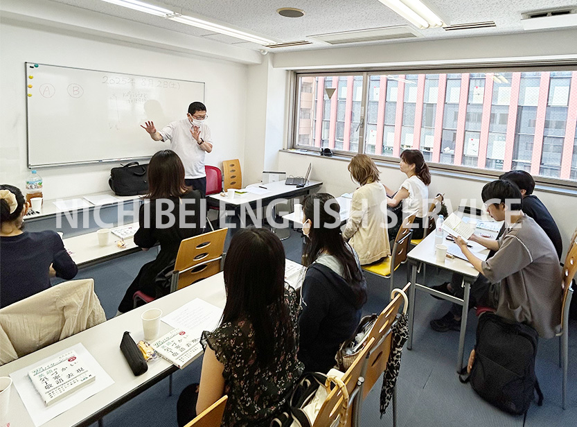 ホワイトボードを指さす津村先生と熱心に受講する生徒の皆様