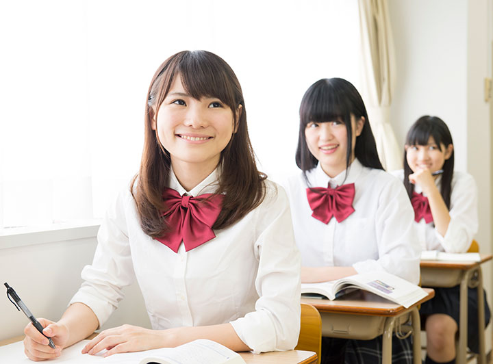 正面を向いて教室で授業を受ける女子高校生のイメージ画像