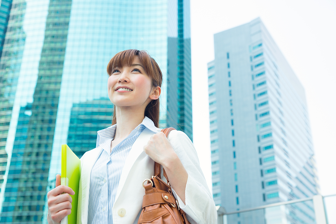 オフィス街が笑顔で青空を見つめる女性