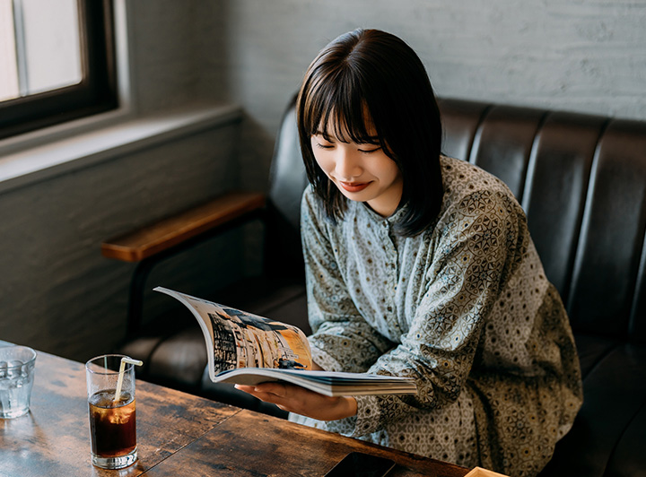 カフェでくつろぎながら本を読む女性のイメージ画像