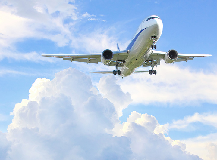 青空を飛んでいる飛行機を下から見上げた写真