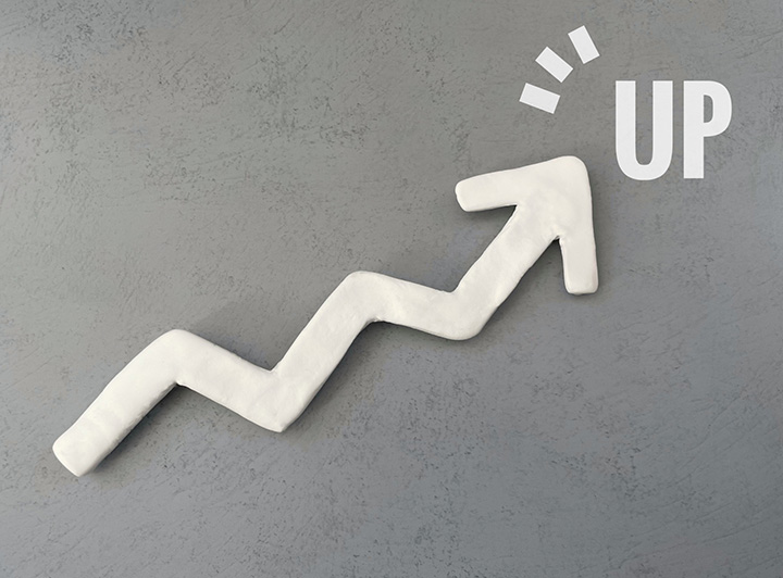 灰色の背景に粘土でできた矢印が左下から右上にかけて伸びている。同じ素材でUPと書かれている。