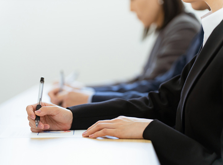 スーツ姿で試験を受けている大学生のイメージ